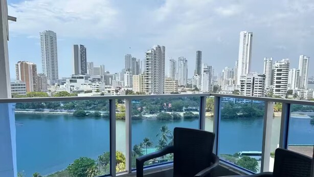 Un balcón con vistas a un horizonte urbano y una masa de agua.