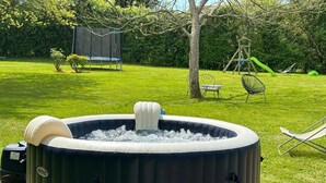 A hot tub in a backyard with a trampoline, a swing set, and a dining table. - Magnifique Maison Avec Pisicne a 40 mn de la mer (Livarot-Pays-d'Auge)
