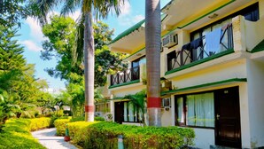 A two-story hotel with balconies, a paved walkway, and lush greenery. - Maya The Forest Resort (Ramnagar)