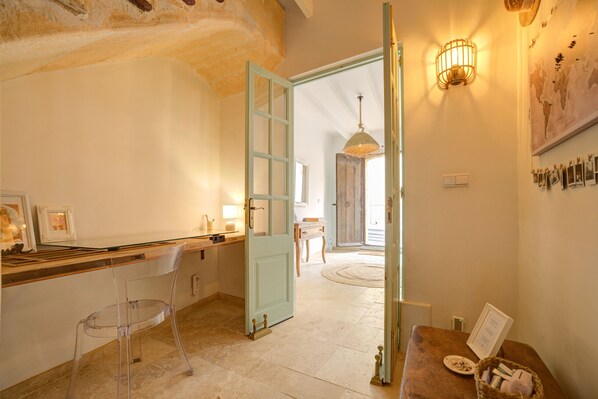 A room with a wooden counter, a clear plastic chair, a light blue door, and a wall-mounted light fixture.