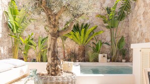 A pool area with a stone wall, a tree, and various plants. - Petra holiday home by Rentallorca (Petra)