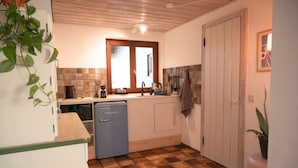 A compact kitchen with a dishwasher, a sink, and a window above it.