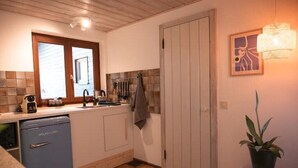 A compact kitchen with a dishwasher, a sink, and a tiled backsplash.