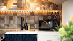Una cocina con salpicadero de azulejos, microondas y pileta.
