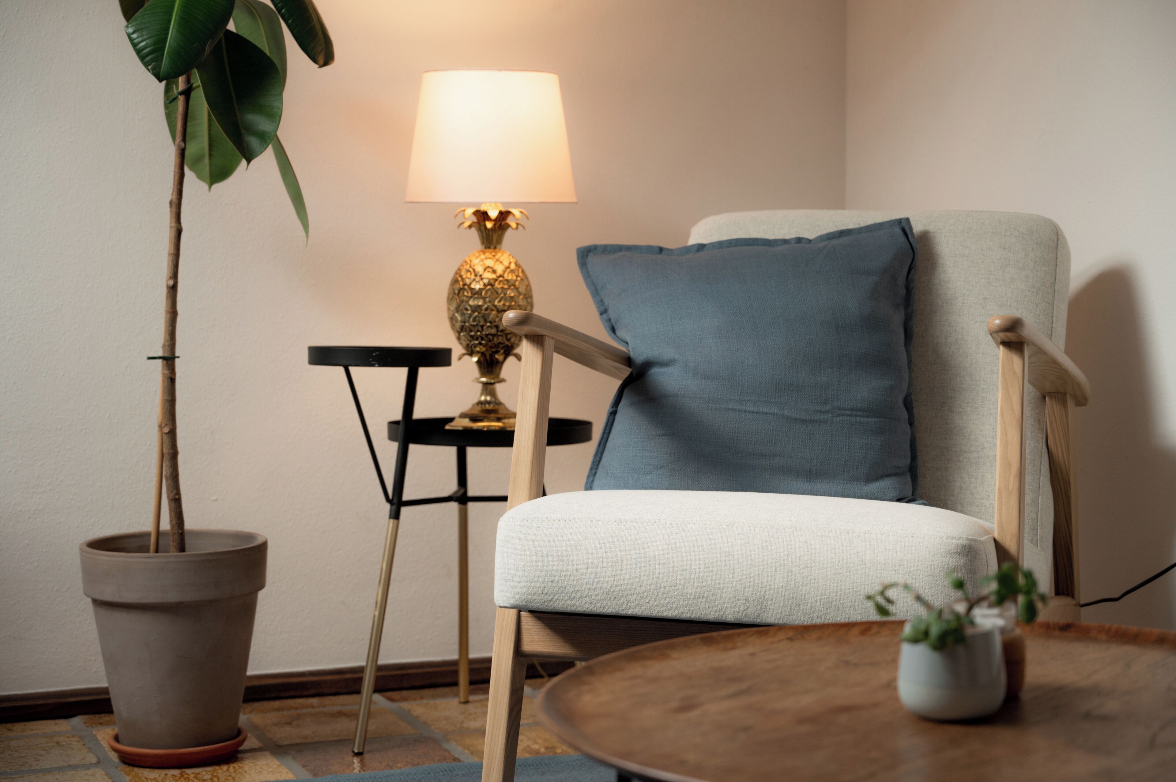 A room with a chair, a table, a lamp, and a potted plant.