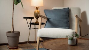 Una habitación con una silla, una mesa, una lámpara y una planta en maceta.