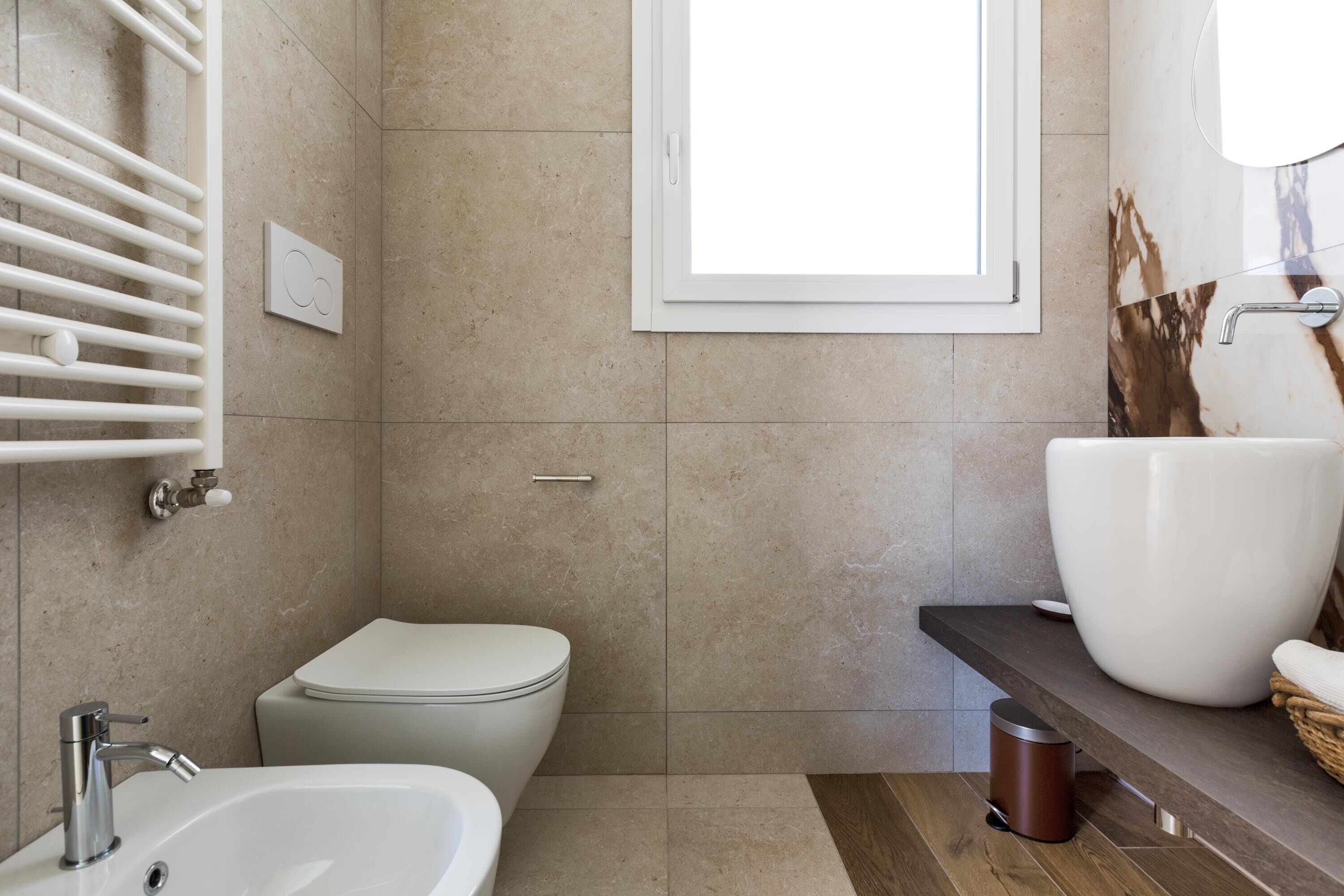 Un baño moderno con un lavamanos blanco, un inodoro y un espejo grande.