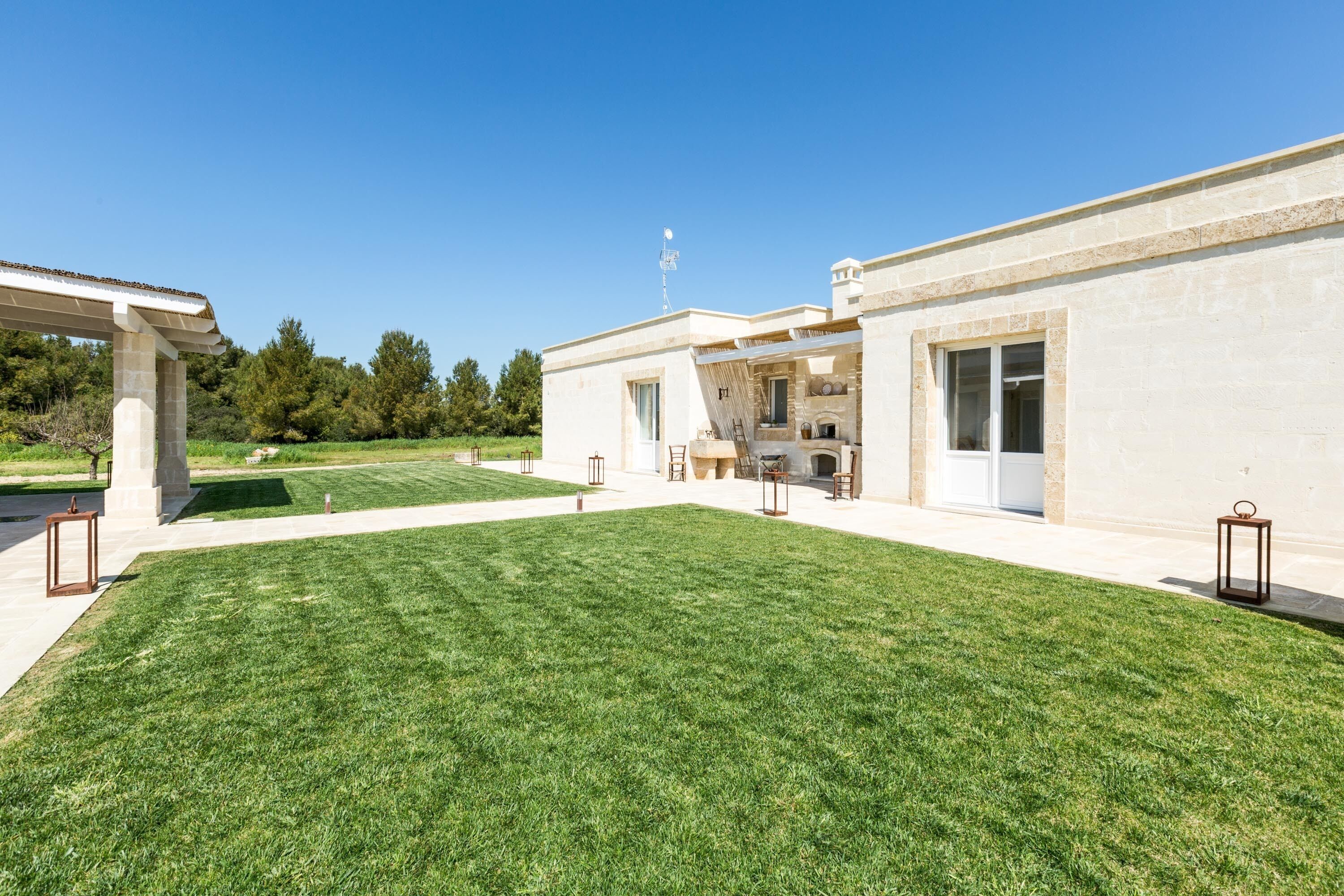 Une maison moderne dotée d’une pelouse bien entretenue, d’un patio couvert et d’une cheminée bien visible.