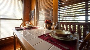 A dining table set with plates, glasses, and a vase of flowers. - Heart Shaped Tub for Two, Cabin, Views for miles! (Eureka Springs)