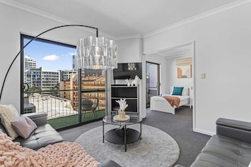 Inviting living room bathed in natural light, featuring a modern aesthetic, direct balcony access, and an adjoining flexible sleeping space.