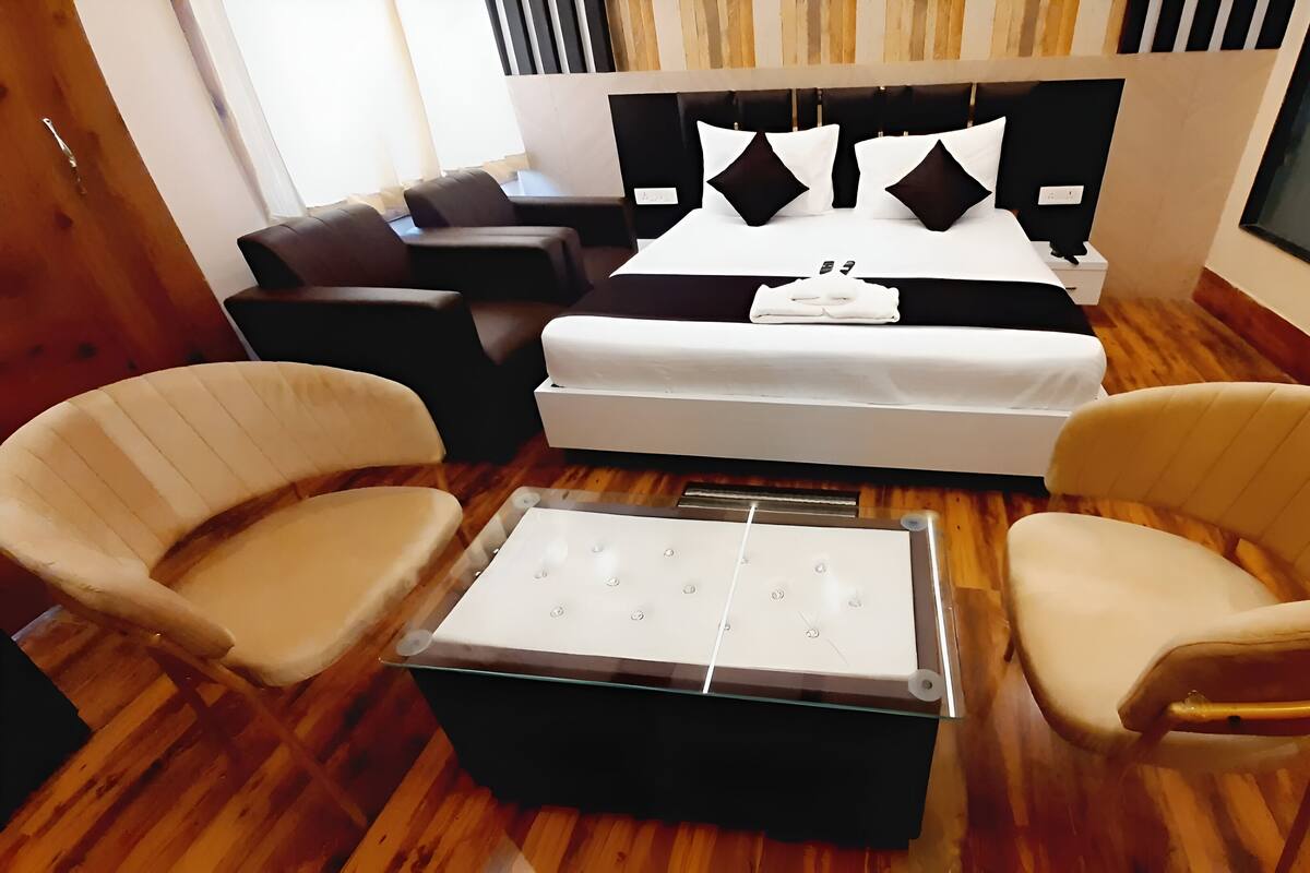 Ein Hotelzimmer mit einem Bett, zwei Sesseln, einem kleinen Tisch und einem Fernseher.
