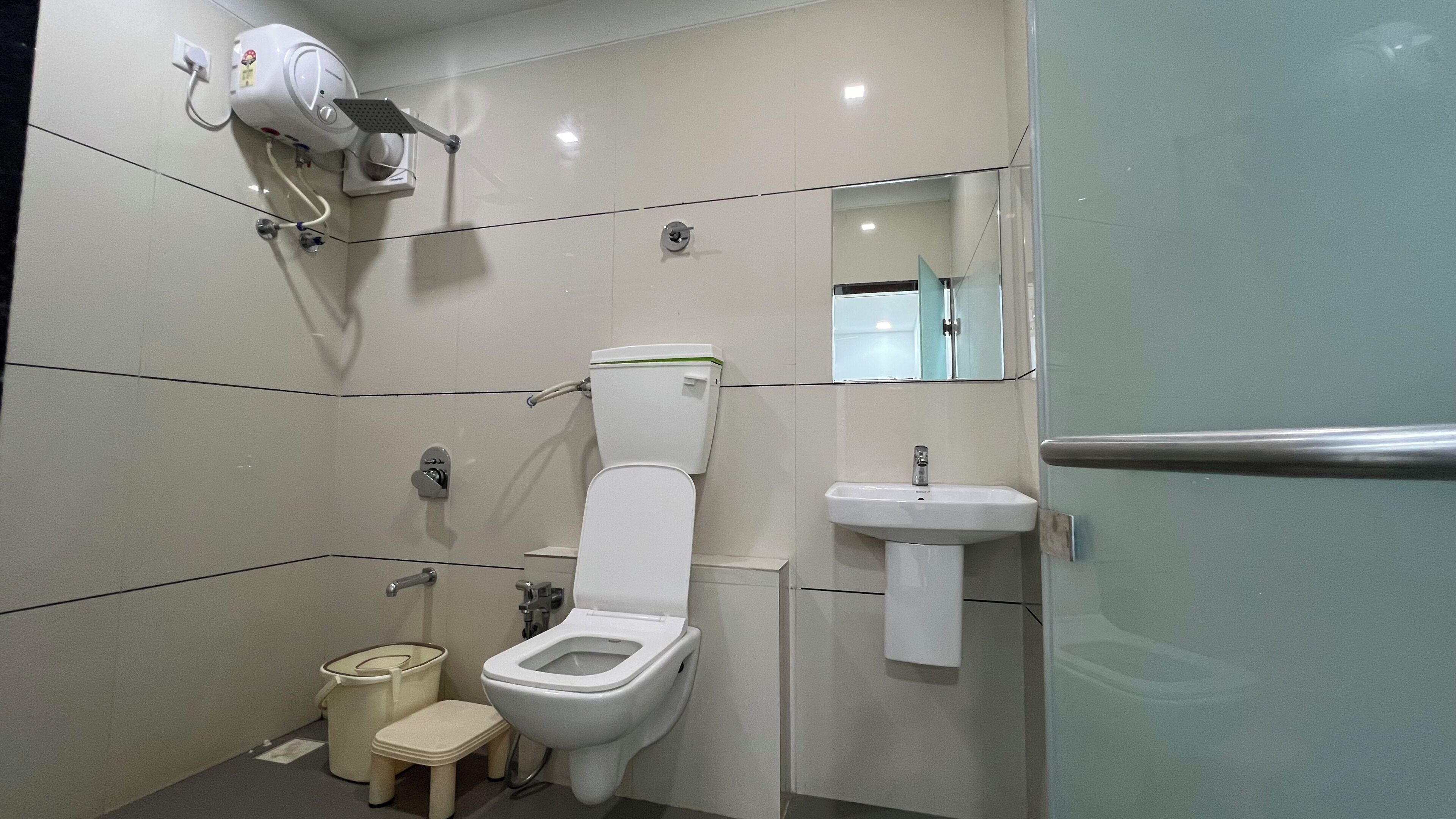 A modern bathroom with a toilet, bidet, sink, and a mirror.