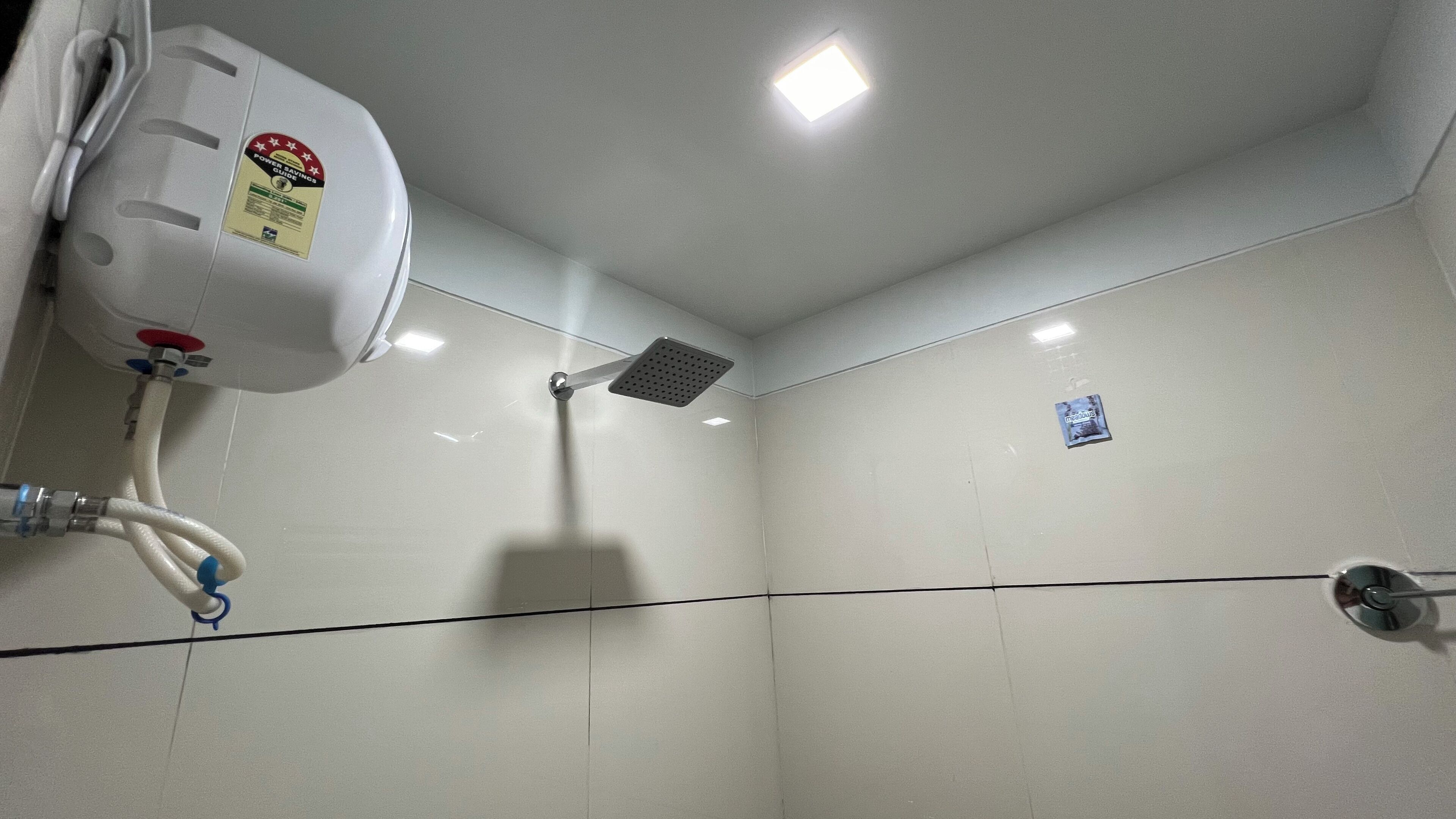 A bathroom with a shower, a toilet, and a hand dryer.
