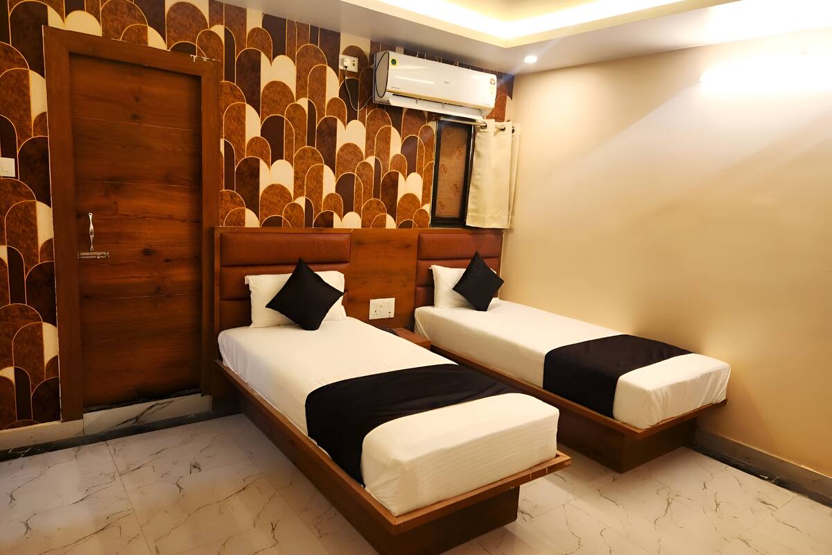 Ein Hotelzimmer mit zwei Betten, einem Holzkopfende, einer Wand mit Muster und einer Klimaanlage.