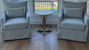 Una habitación con dos sillones grises orientados hacia un ventanal con vistas a un cuerpo de agua.