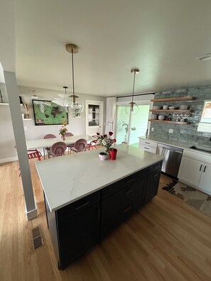 A modern kitchen with a large island, wooden cabinets, and pendant lighting. - Family home by CU (Boulder)