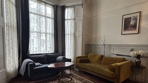 A living room with a dark sofa, a yellow sofa, a coffee table, a patterned rug, and a framed picture on the wall.