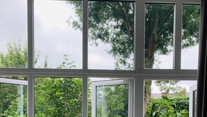 A room with a large window overlooking a lush garden.