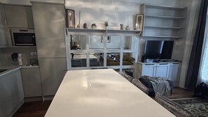 A modern kitchen with a central island, built-in appliances, and a dining area with a sofa and TV.