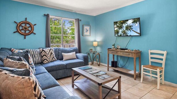 Un salon avec un canapé bleu, une table basse en bois, un bureau en bois et une chaise.