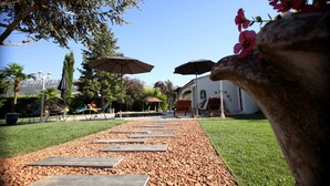 A pathway leading to a building with outdoor seating and umbrellas. - Magnifique Villa avec Piscine/Jacuzzi tout confort (Nans-les-Pins)