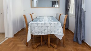 Une table à manger recouverte d’une nappe à motifs géométriques, des chaises en bois et un miroir placé au-dessus.