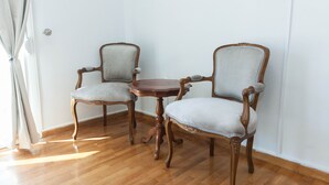 Une pièce avec deux chaises en bois et une petite table, un plancher en bois et un mur blanc.