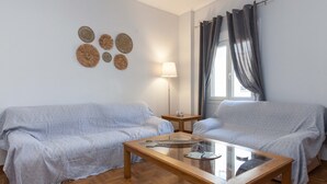 Une pièce avec deux canapés de couleur gris clair, une table basse en bois, une lampe et des œuvres d’art décoratives accrochées au mur.