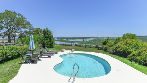 A swimming pool with a curved edge, surrounded by a white deck, and overlooking a body of water. - Gorgeous Inlet View Pet Friendly 3 BR Home with a Private Pool! Kohler's Cottage (Murrells Inlet)