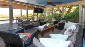 A covered outdoor seating area with wicker furniture, a wooden coffee table, and a flat-screen TV. - Gorgeous Inlet View Pet Friendly 3 BR Home with a Private Pool! Kohler's Cottage (Murrells Inlet)