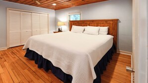 A bedroom with a large bed, wooden floor, a wardrobe, and a window with blinds. - Gorgeous Inlet View Pet Friendly 3 BR Home with a Private Pool! Kohler's Cottage (Murrells Inlet)