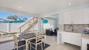 A modern kitchen with white cabinets, a built-in sink, and a dining area with a table and chairs.