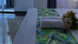 Ein Hotelzimmer mit Bett, Blumen und Blick durch das Fenster.