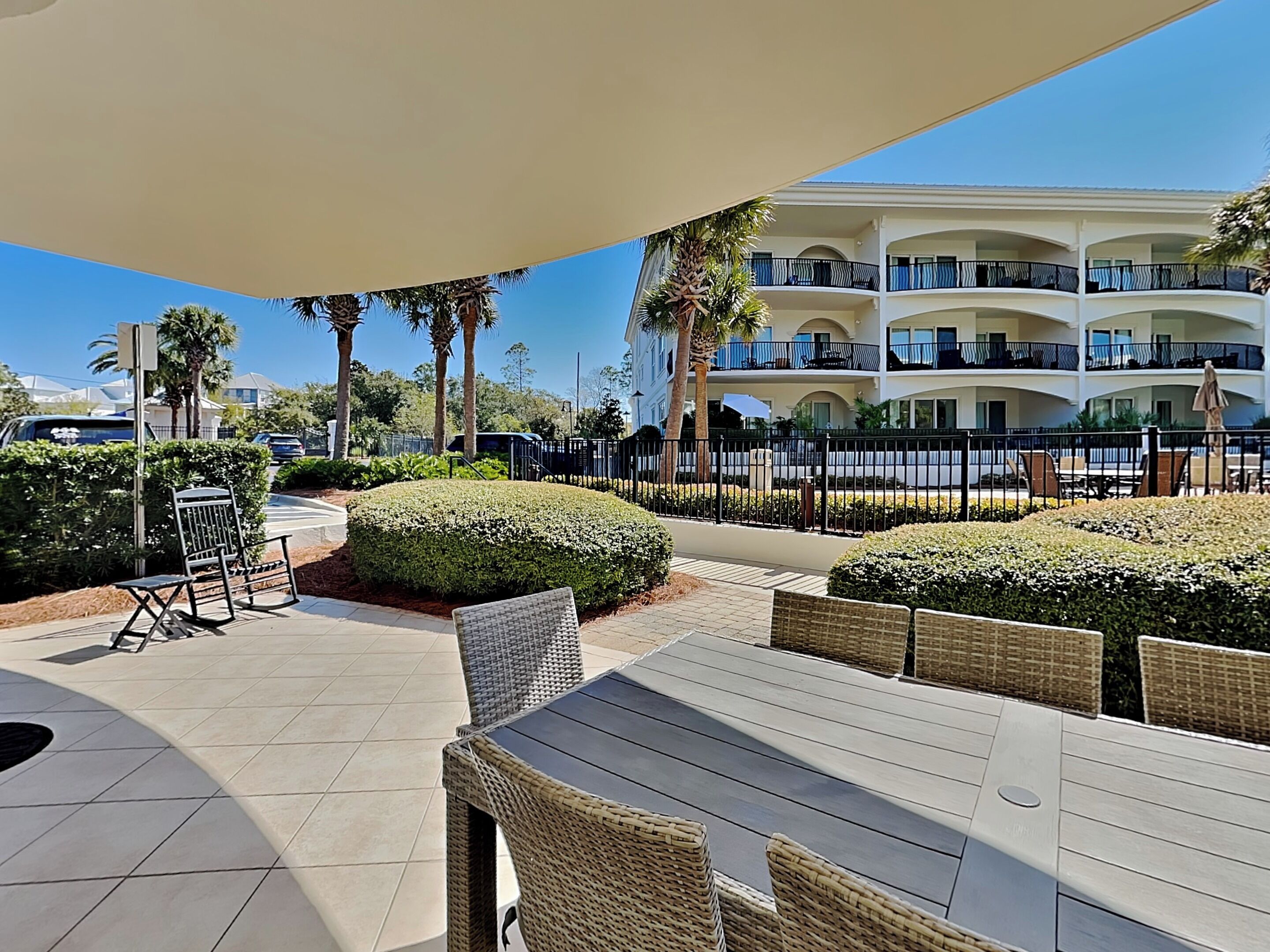 Eine Hotelterrasse mit Sitzgelegenheiten im Freien, einem Pool und einem mehrstöckigen Gebäude mit Balkonen.
