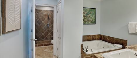 A modern bathroom with a walk-in shower, a large bathtub, and a sink.