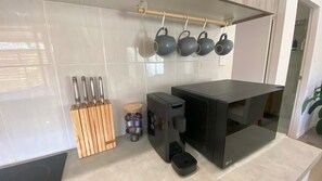 A kitchen with a black countertop, hanging pots, a knife block, and a black appliance. - Charming Beach Getaway -Tucked away in Valla beach is the charming home that has a unique private ba (Valla Beach)