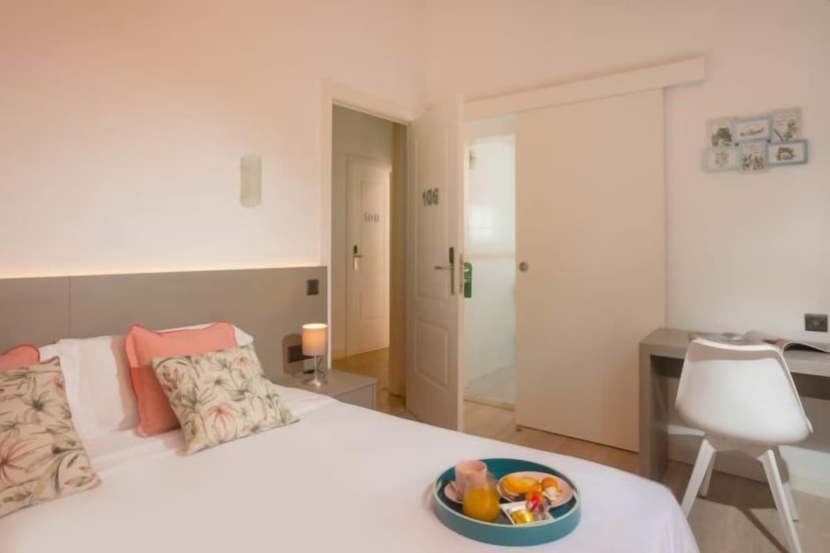 Ein Hotelzimmer mit Bett, Schreibtisch, Stuhl und Frühstückswagen.