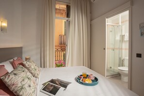 A hotel room with a bed, a breakfast tray with eggs, toast, and juice, and a bathroom with a glass shower. - Antonios Hostal (Sitges)