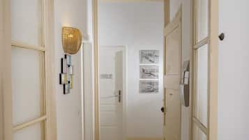 A hallway with a white door labeled "102", a wall-mounted light fixture, and framed pictures.