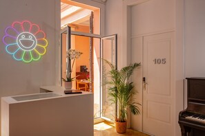 A modern interior with a piano, a neon flower sign, and a door labeled 105.