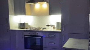 A modern kitchen with grey cabinets, a built-in oven, a gas stove, and under-cabinet lighting.