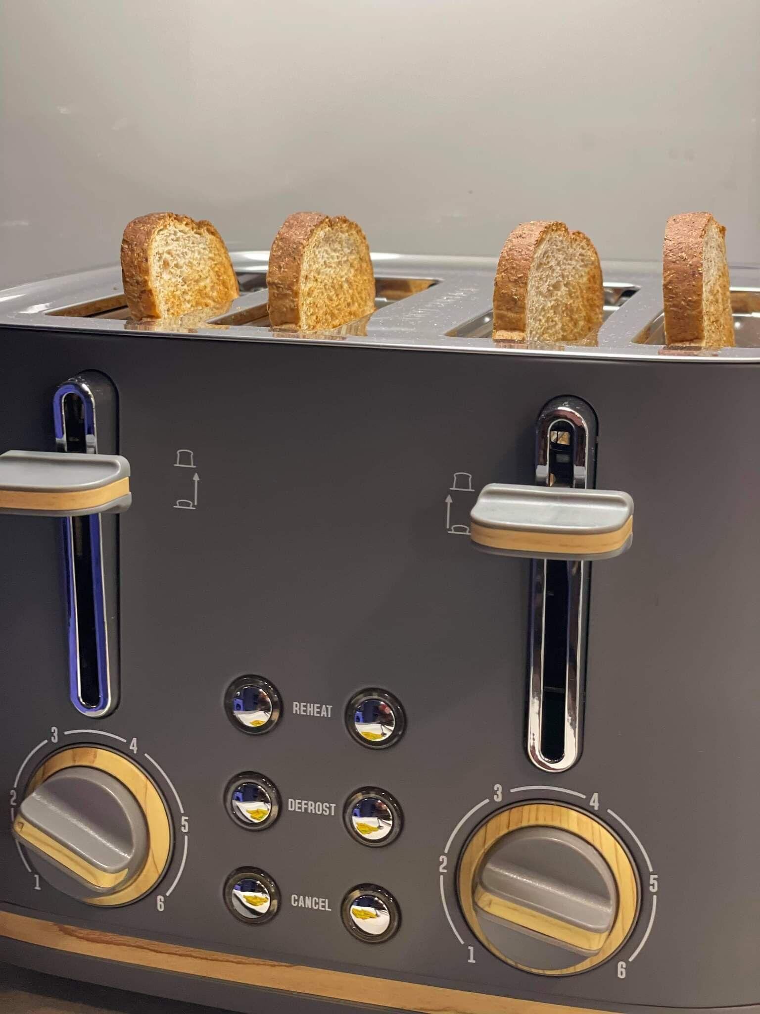 Un tostador con cuatro ranuras, cada una sosteniendo una rebanada de pan.