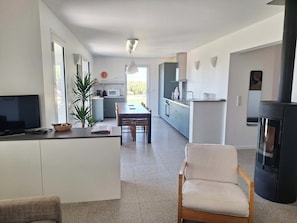 A modern kitchen with a dining area, a TV, and a fireplace.