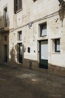 Un edificio de piedra con varias puertas y ventanas, algunas con contraventanas.