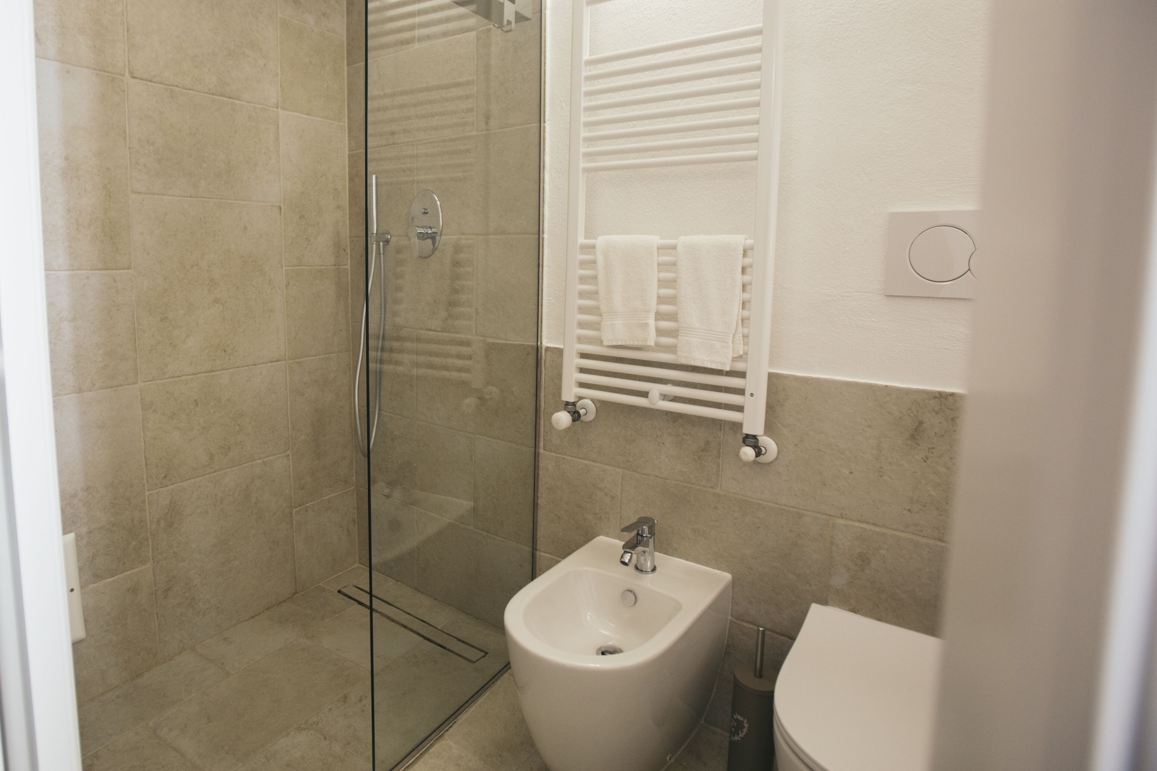 A modern bathroom with a glass-enclosed shower, a white sink, and a towel rack.