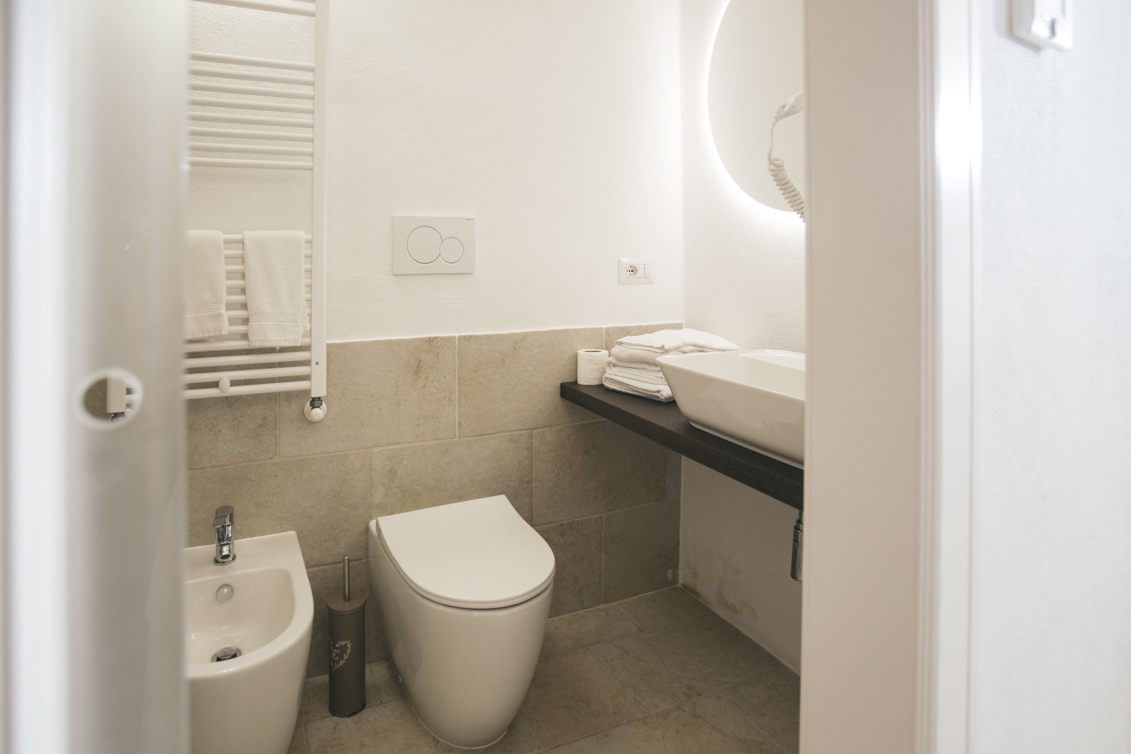 Een moderne badkamer met een bidet, toilet, wastafel en handdoekhouder.