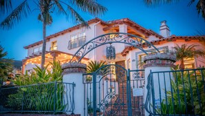 Uma casa de dois andares com varanda, portão e escada que leva à entrada.