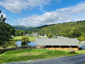 A rural setting with a large tent-like structure, a pond, and a road.