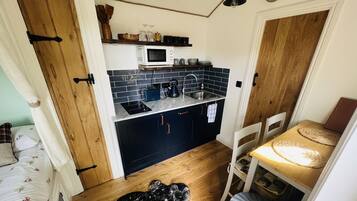 Una cocina compacta con microondas, fregadero y armarios de madera.