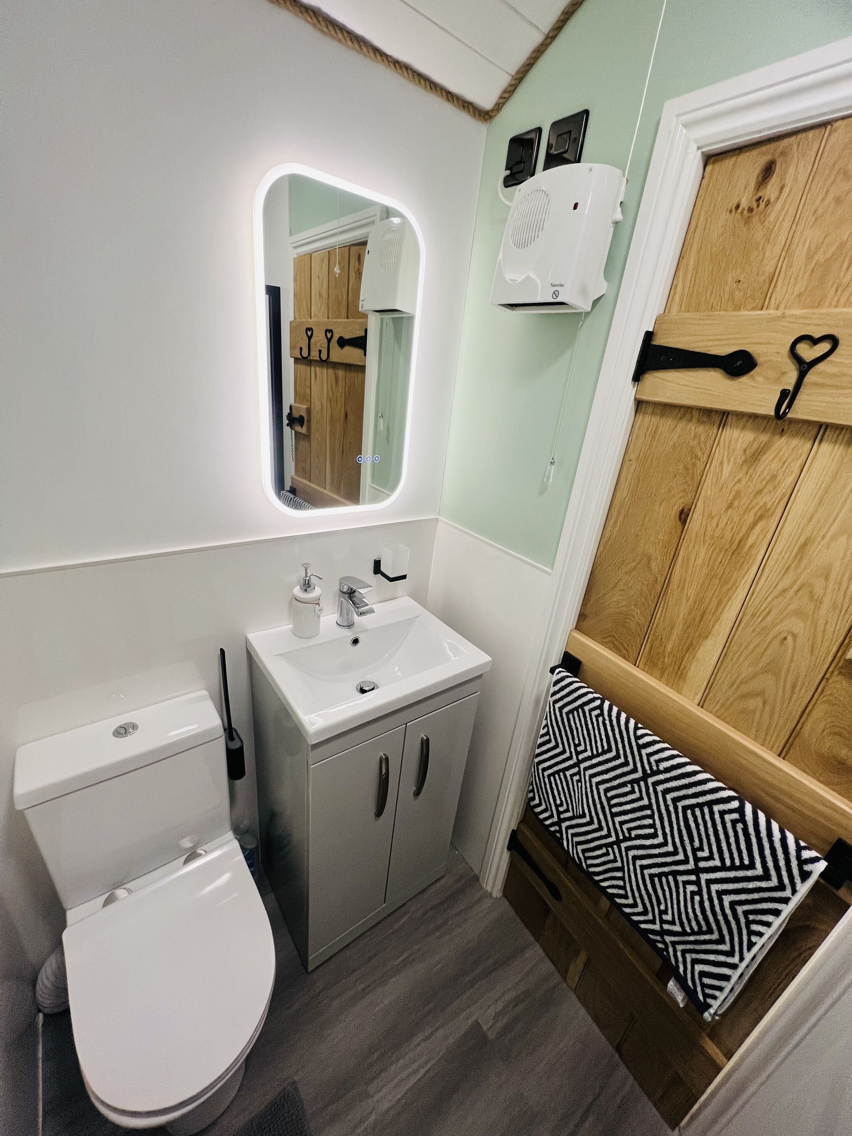 A compact bathroom with a toilet, sink, and mirror.